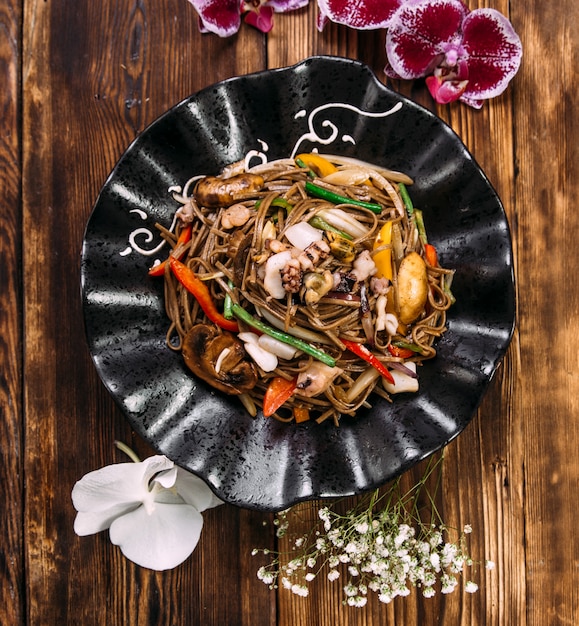 A beautifully arranged plate of Japchae, featuring colorful glass noodles mixed with stir-fried vegetables like carrots, bell peppers, spinach, and mushrooms, garnished with sesame seeds. The noodles should have a slightly glossy appearance and the vegetables should be brightly colored and crisp-looking.