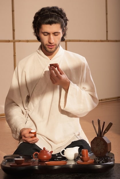A side-angle photo of a person dressed in traditional Korean hanbok carefully pouring tea into a small porcelain cup during a tea ceremony. The background is softly blurred, highlighting the focus on the tea-pouring process.