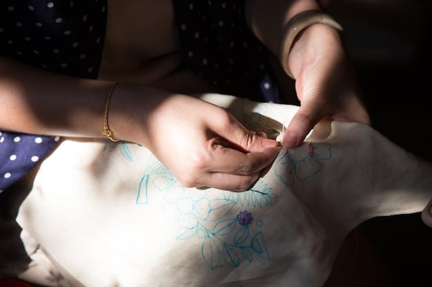Hands working on a piece of Korean embroidery, focusing on a specific stitch with a needle and thread. The fabric is stretched on an embroidery hoop, and the background is slightly blurred to emphasize the detail of the stitching technique.