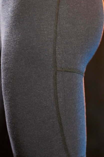 A close-up shot of a pair of athletic leggings. The leggings are dark gray and feature a subtle, repeating pattern composed of tiny, stylized lightning bolts. The lightning bolts are a deep blue color and almost blend into the background, making the pattern noticeable only upon closer inspection.