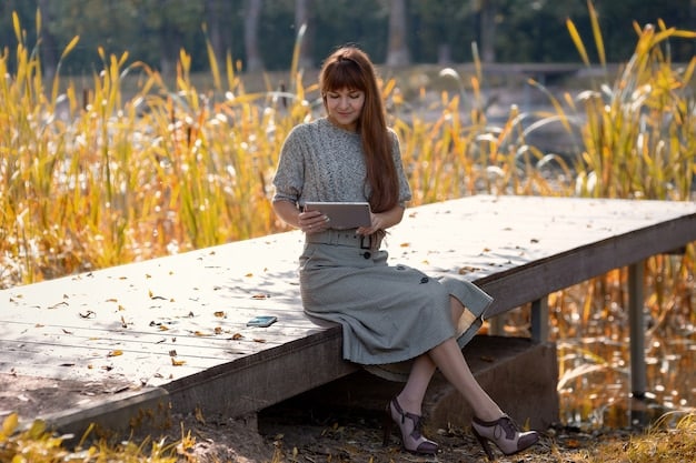 A young woman is sitting on a park bench, reading a book. She is wearing an oversized, dark green sweater with a faded logo of a fictional university. She also has on distressed jeans and a pair of combat boots. The overall look is comfortable, stylish, and slightly rebellious.