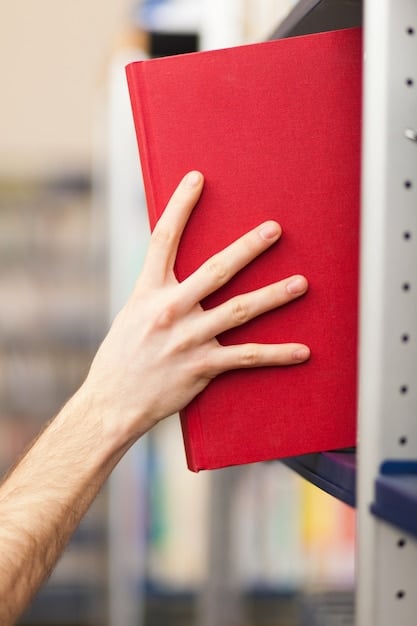 A close-up shot of a human hand selecting a science fiction novel from a shelf filled with books. The selected book has a vibrant, abstract cover, contrasting with the more muted tones of the other books.