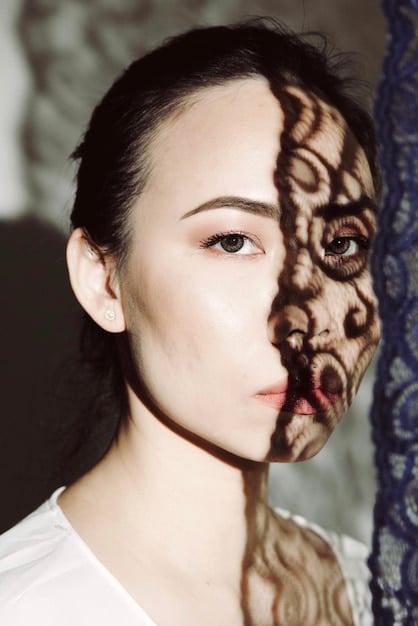 A close-up shot of a cosplayer's face showing intricate makeup details and a determined expression, captured using only natural light from a nearby window.