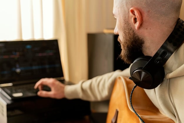 A close-up of a composer in a recording studio, wearing headphones and intently watching a screen displaying musical notation software. Microphones and instruments are visible in the background.