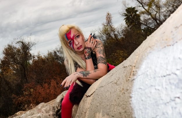 A photographer crouched down, focusing his camera on a cosplayer dressed as Wonder Woman, posing heroically in a field of wildflowers under a bright, diffused sunlight. Other photographic equipment is visible nearby, suggesting a professional shoot.