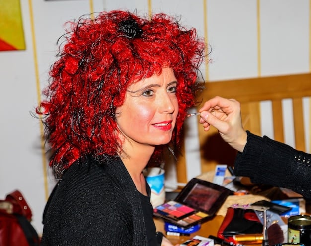 A cosplayer applying intricate makeup to their face, using various brushes and palettes. The makeup is detailed and expressive, capturing the essence of the character they are portraying.