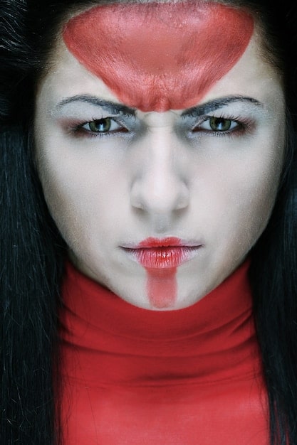 A detailed and close-up shot of a cosplayer dressed as a popular anime character, demonstrating intricate costume design and makeup artistry at a US anime convention. The background shows blurred attendees and convention decor.