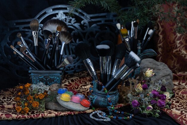 A close-up shot of a cosplayer's workbench, filled with various tools and materials such as fabric swatches, foam pieces, paintbrushes, a sewing machine, and a mannequin head with partially applied makeup.