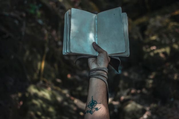 A player's hands are shown holding a Dungeons & Dragons Player's Handbook. The book is open. In the background, there are various other RPG books and accessories. The image highlights the tangible and immersive aspects of the tabletop hobby.