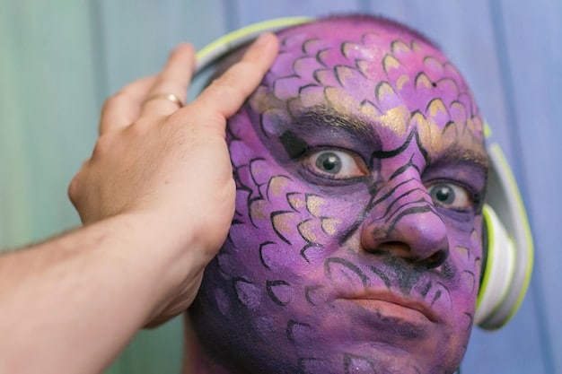 A cosplayer applying intricate makeup to their face, transforming their appearance to resemble their chosen character. The image focuses on the details of the makeup application and the specific products used.