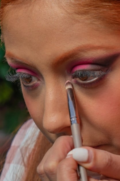 A detailed close-up showing various makeup brushes and vibrant eyeshadows being used to create an intricate character look. The focus is on the precision and artistry of the makeup application.