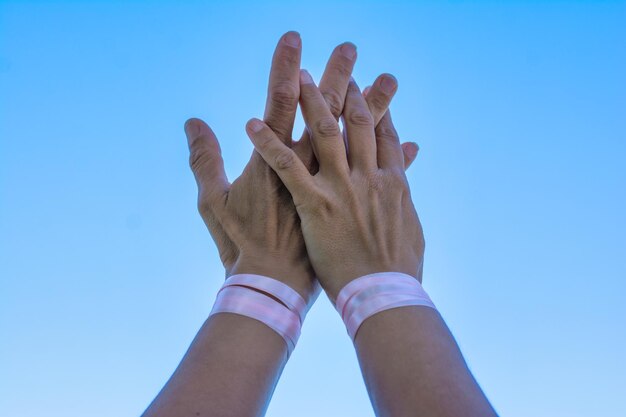 Three distinct hands reaching towards a glowing K-Pop album cover, each wearing a bracelet representing different aspects of copyright: a musical note, a camera, and a writing quill, symbolizing song composition, video creation, and written content copyright.
