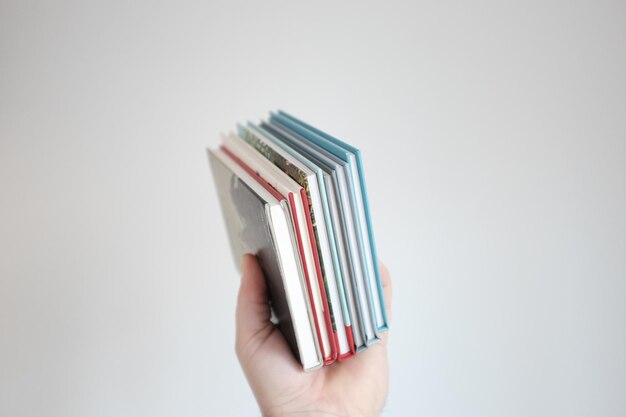 A close-up shot of various K-Pop albums stacked neatly, highlighting the album designs and packaging. A hand is reaching to grab an album from the stack.