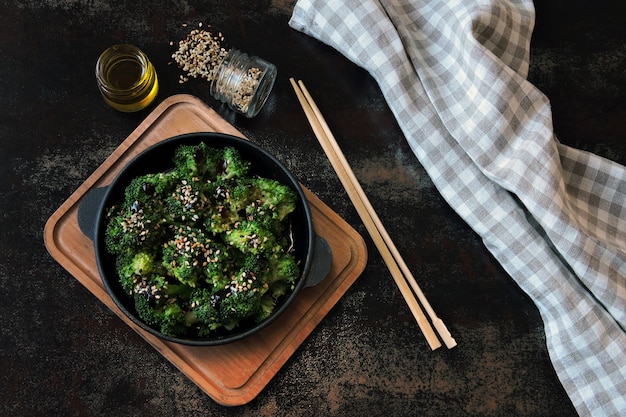 Overhead shot of a vegan bibimbap bowl filled with colorful vegetables, marinated tofu, and gochujang sauce, topped with sesame seeds. The bowl is set on a rustic wooden table with chopsticks.