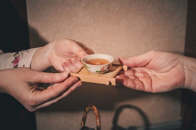 A close-up of a participant's hands respectfully receiving a cup of tea during a Korean tea ceremony. The focus is on the act of receiving with both hands, demonstrating the proper etiquette.
