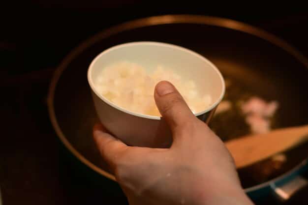 A close-up shot of Tteokguk (rice cake soup) being served in individual bowls during a Seollal celebration in a Korean-American household. The focus is on the savory broth, colorful garnish, and the comforting steam rising from the bowls, emphasizing the warmth and familial atmosphere.