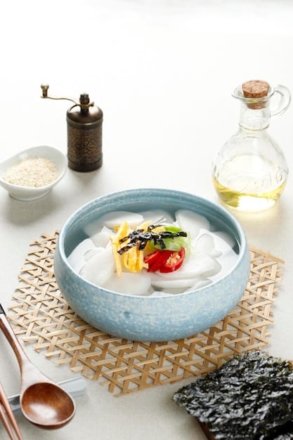 A close-up shot of a bowl of Tteokguk (rice cake soup) being served during a Seollal celebration in the US. The soup is garnished with seaweed and egg, and steam rises from the bowl.