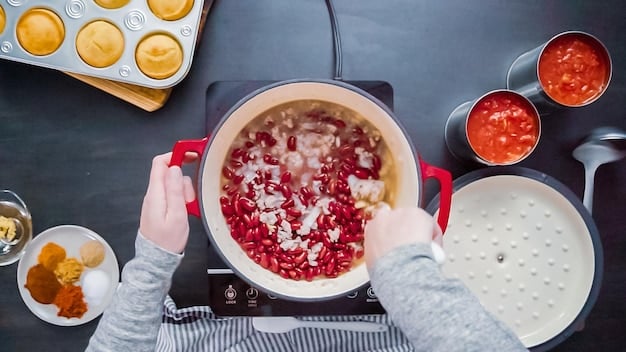 A chef mixing kimchi paste in a large stainless steel bowl. The vibrant red color of the paste contrasts with the metallic bowl, and the chef's hands are visible as they mix the ingredients.