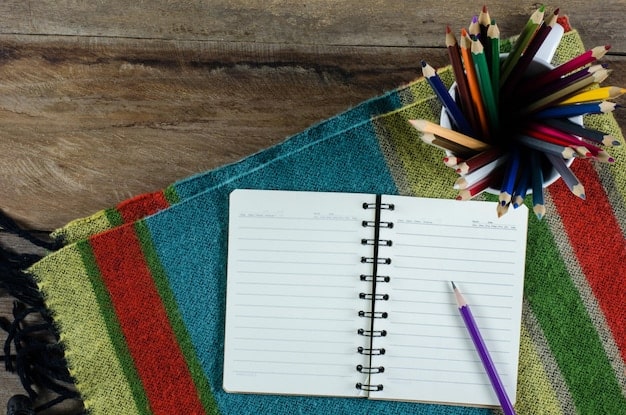 A close-up of a notebook with handwritten Korean vocabulary words and their English translations, surrounded by colorful pens and sticky notes.