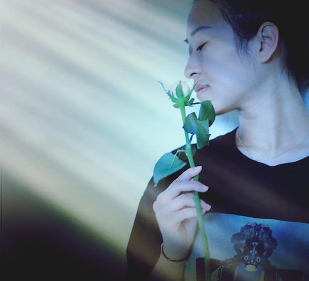 A close-up shot of a K-Pop artist holding a single blooming flower, with soft lighting emphasizing the delicate details of the petals and conveying themes of beauty, fragility, and growth.