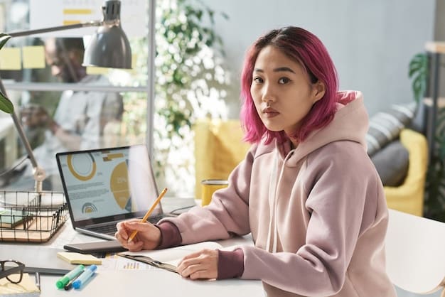 A young woman sitting at a desk, studying Korean Hangul characters on her laptop with a focused expression. Korean textbooks and notebooks surround her.