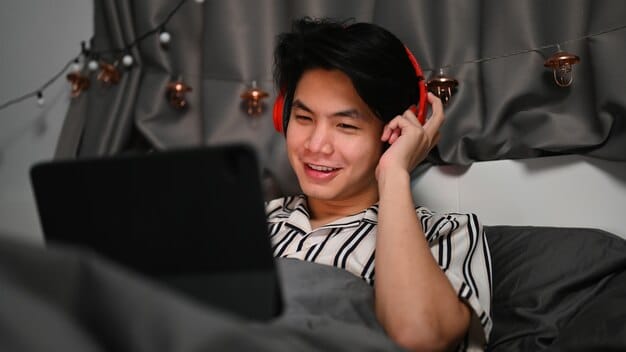A person wearing headphones and watching a K-drama on a laptop, with Korean subtitles displayed on the screen. The background is cozy and inviting, suggesting a relaxed study environment at home.