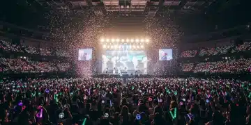 Energetic K-Pop concert crowd with lightsticks and idols performing on stage.