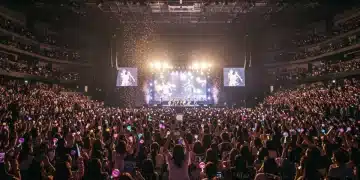 K-Pop group performing live on stage at a sold-out US arena concert, with enthusiastic fans.