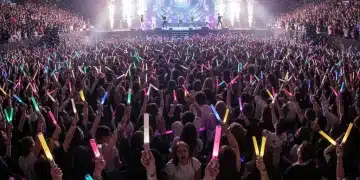 K-Pop fans at a concert holding lightsticks, showcasing collective fandom power.