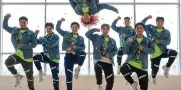 Energetic young adults performing a synchronized K-Pop dance cover in a studio.